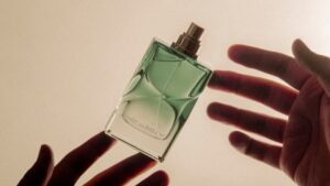 柔らかな光に包まれた香水瓶と手元。美しさの裏に潜む香害の静かな問いかけ