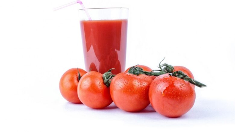 グラスに入ったトマトジュースと、その手前に並べられた新鮮なトマト。