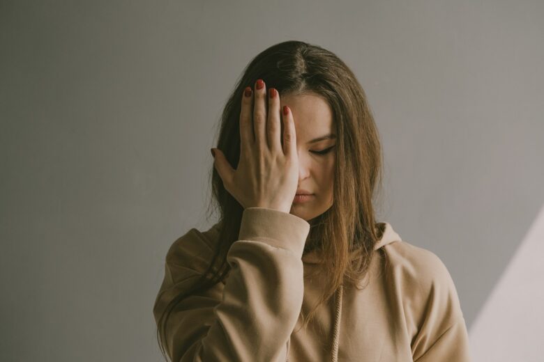 香害による頭痛や不調を感じる女性のイメージ。合成香料の匂いで体調を崩しやすい更年期世代の症状を表す。