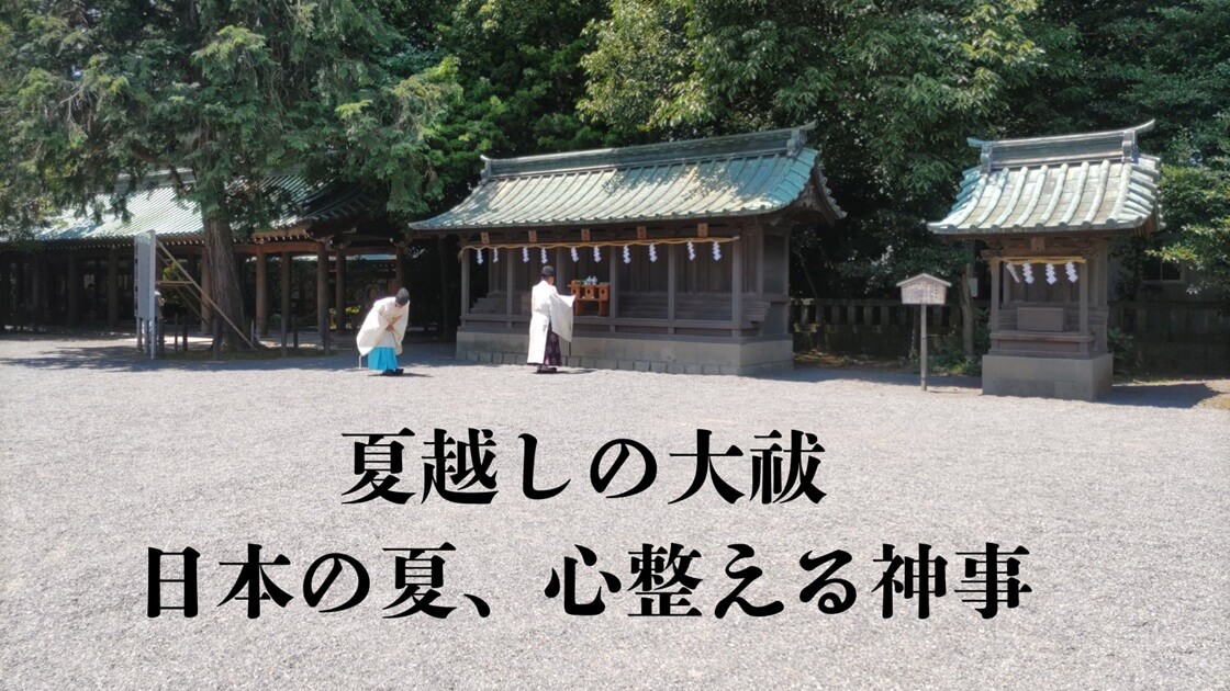 広々とした砂利の境内にある、複数の木造社殿。緑の瓦屋根が特徴的で、手前では白い装束を身につけた二人の人物（神職または巫女）が、社殿に向かって儀式を行っている。周囲は豊かな木々に囲まれ、静かで神聖な雰囲気が漂う神社の様子。黒文字で「夏越しの大祓 日本の夏、心整える神事」と表示。