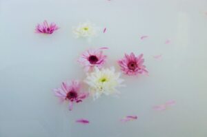 更年期のセルフケアとしてのアロマバスイメージ。白いお湯の中にピンクと白の花びらが静かに浮かぶ、おうちリトリートの癒やしのひとコマ。