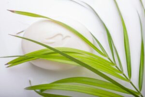 更年期のニオイ対策に、自然由来の石鹸でやさしくケア。白い石鹸とグリーンの葉がシンプルに並ぶ清潔感のある一枚。
