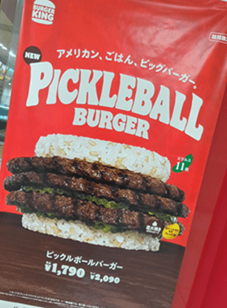 バーガーキングのピックルボールバーガーのポスター。ご飯のバンズと3枚のパティ、大量のピクルスが特徴。