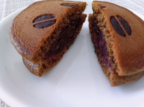 半分にカットされた鼓かさねの断面。コーヒー味の生地に、甘さ控えめの粒あんが挟まれた和菓子の内部構造。