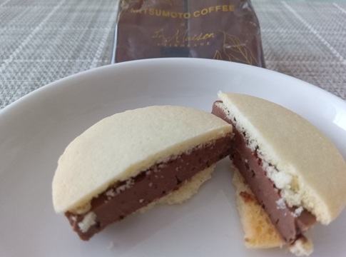 羽田空港限定「カフェショコラウィッチ」キャラメルラテ味の断面。バニラ風味のクッキーと、粗挽きコーヒー入りのキャラメルショコラ。