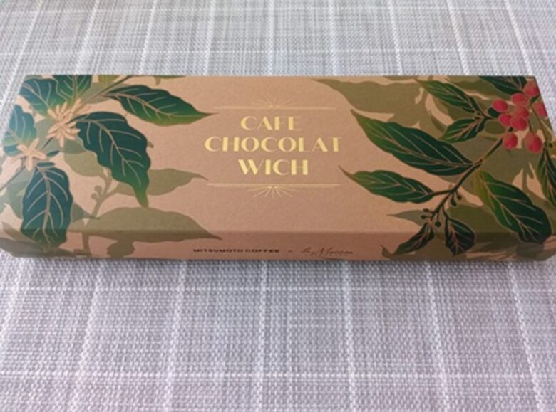 コーヒーの木のイラストと金色のロゴがデザインされた、羽田空港限定「カフェショコラウィッチ」のパッケージ外観。