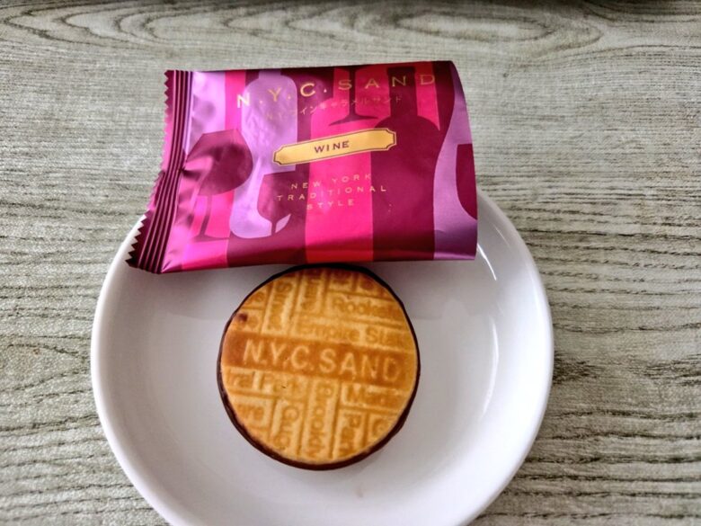 N.Y.ワインキャラメルサンドのルビー色の個包装と、NYCSANDのロゴが刻まれたクッキー